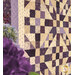 A stylized close up on the quilt, taken at a slight angle; coordinating flowers peek into frame from the lower left frame.