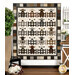 The completed Charming Lambs quilt colored in earthy neutrals from the Woolies Flannel collection, depicting five rows of four lambs behind little fence doors, hung on a white paneled wall and staged with coordinating farmhouse decor.