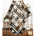 The completed Charming Lambs Quilt in soft and muted fabrics from the Woolies Flannel collection, artfully draped from a wooden quilt ladder and staged with coordinating farmhouse decor.