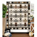 The completed Charming Lambs quilt colored in earthy neutrals from the Woolies Flannel collection, depicting five rows of four lambs behind little fence doors, hung on a white paneled wall and staged with coordinating farmhouse decor.