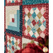 A stylized close up on the two types of blocks of the quilt, taken at a slight angle with coordinating flowers peeking into frame from the right side.