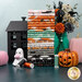 A stack of the fabrics included in the Frank and Friends FQ bundle, with a jar and flowers and pumpkins and a house and a jack o'lantern and a ghost and thread.