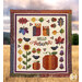 The completed Hello Autumn quilt being held up by someone in front of a golden field and mountains against a bright, shining sky.