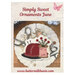 Front cover of the pattern showing the completed project on resting on a plate of quilting notions.
