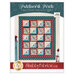 Front cover of the pattern featuring the completed quilt in ocean blue, brick red, and sandy cream, staged on a cream wall with coordinating decor.