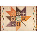 A close up on the autumn leaf in the center of the quilt, demonstrating fabric, piecing, flying geese, and border details.