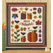 The completed Hello Autumn quilt colored in the warm reds, greens, yellows, and creams from the Autumn Breeze collection, hung on a rustic tan-paneled wall and staged next to autumnal flowers sitting on a small green cabinet.