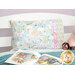 A stylized shot of the pillow on a white bed, staged with an open children's book beside a stuffed unicorn toy.