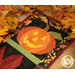 A close up on a jack-o-lantern block, framed by decorative fall leaves on a wooden tabletop.