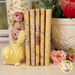 A stack of fabrics included in the Ruru Bouquet - Yellow collection, with a pot and flowers and a bottle and a bird statue.