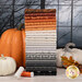 A stack of the fabrics included in the Nightfall collection, with pumpkins and a window and spooky trees and leaves and thread.