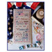 A image of the completed Pledge of Allegiance cross stitch pattern staged with an American flag and sewing notions.