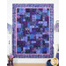 The completed Easy as ABC quilt in purple, blue, and lavender batik fabrics from the Wisteria Blooms collection by Bali Batiks, staged with coordinating décor and white furniture.
