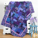 The completed Easy as ABC quilt in purple, blue, and lavender batik fabrics from the Wisteria Blooms collection by Bali Batiks, artfully draped over a hutch and staged with coordinating décor.