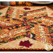An angled close up on the quilt, demonstrating details on how the patchwork meets in the middle as well as showing fabric details on the appliqué leaves.