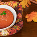 A top-down image of the bowl cozy holding a bowl of tomato soup, surrounded by coordinating autumn leaf decor.