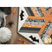 A stylized shot of half the table topper, staged with spooky Halloween decor and candy.