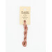 A skein of light muted pink embroidery floss, twisted and bundled, with a cream and black label featuring the brand name and color information.