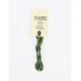 A skein of sage green embroidery floss, twisted and bundled, with a cream and black label featuring the brand name and color information.