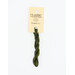 A skein of forest green embroidery floss, twisted and bundled, with a cream and black label featuring the brand name and color information.