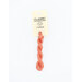A skein of coral orange embroidery floss, twisted and bundled, with a cream and black label featuring the brand name and color information.