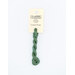A skein of muted green embroidery floss, twisted and bundled, with a cream and black label featuring the brand name and color information.