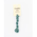 A skein of teal embroidery floss, twisted and bundled, with a cream and black label featuring the brand name and color information.