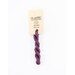 A skein of purple embroidery floss, twisted and bundled, with a cream and black label featuring the brand name and color information.