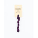 A skein of dark plum embroidery floss, twisted and bundled, with a cream and black label featuring the brand name and color information.