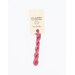 A skein of coral pink embroidery floss, twisted and bundled, with a cream and black label featuring the brand name and color information.