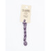 A skein of muted purple embroidery floss, twisted and bundled, with a cream and black label featuring the brand name and color information.