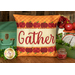 The finished Gather pillow wrap kit, a red and orange wrap with red apple borders and appliqué letters that read 