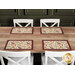 The four completed Self-Binding Placemats, colored in warm autumn fabrics from the Rustle collection by Maywood Studio, staged on a rustic wooden table with white chairs.
