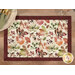A top down shot of one of the placemats, demonstrating details on the cream fabric with a multicolor leaf print and the wine red fabric used for the binding.
