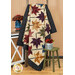The Fluttering Leaves quilt, colored in colorful fabrics from the Flossie's Flowers collection by Henry Glass, artfully draped over a rustic wooden quilt ladder, demonstrating flow and form of the quilt.