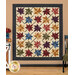 The Fluttering Leaves quilt, colored in colorful fabrics from the Flossie's Flowers collection by Henry Glass and hung on a tan paneled wall and staged with coordinating decor.