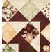 A super close up shot of the patchwork center of the quilt, showcasing fabric, piecing, and top stitched leaf and acorn details.