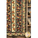 A closer look at the lower right side of the quilt, demonstrating patchwork and appliqué layout, staged beside a wooden ladder holding coordinating decor such as wheat, fabrics in a tin, and books.