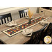 The bonus table runner project staged on a wooden table with a coordinating vase filled with wheat placed in the center, surrounded by four table settings in complementary colors..