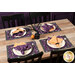 The four placemats in action, staged on a wooden table with four coordinating settings and also using the Witchy Woods cloth napkins.