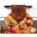A head on shot of the top of the towel, demonstrating details on the leafy fabrics and plaid fabric button.