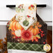 A super close up on the top of the towel, demonstrating details on the pumpkin themed fabrics and plaid fabric button.