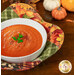 A top down shot of the Bowl Cozy, filled with tomato soup and colored in vibrant autumn-themed fabrics while coordinating decor peeks into frame from the upper right corner.