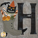 A close up on the H block, featuring a boot full of Halloween treats, a spider, a grinning black cat, and a flying bat.