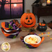 The completed Bowl Cozies colored in black, green, purple, and orange fabrics from the Tonga Haunted Batiks collection, staged on a wooden table with coordinating Halloween decor. One of the cozies holds a white bowl with vanilla ice cream and candy corn.