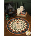 The completed Point of View Folded Star Table Topper colored in black, orange, green, and cream fabrics from the Home Sweet Haunt collection. The topper is staged on a wood table with coordinating Halloween decor and tableware.