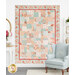 The completed Easy as ABC and 123 quilt, colored in pink, blue, and cream fabrics from the Muse collection by Moda Fabrics, staged on a white paneled wall with coordinating furniture and decor.