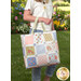 The finished magic charm pack tote kit with a model in a garden scene with flowers in the background. 