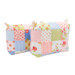 Two finished mini-charm bags with hanging charms and patchwork design made from blue, pink, green, and white fabric from the Memory Lane collection by Moda, isolated on a white background.