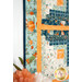 A stylized, angled shot of the wall hanging, showing border and binding details as coordinating fall-themed decor peeks into frame from the left side.
